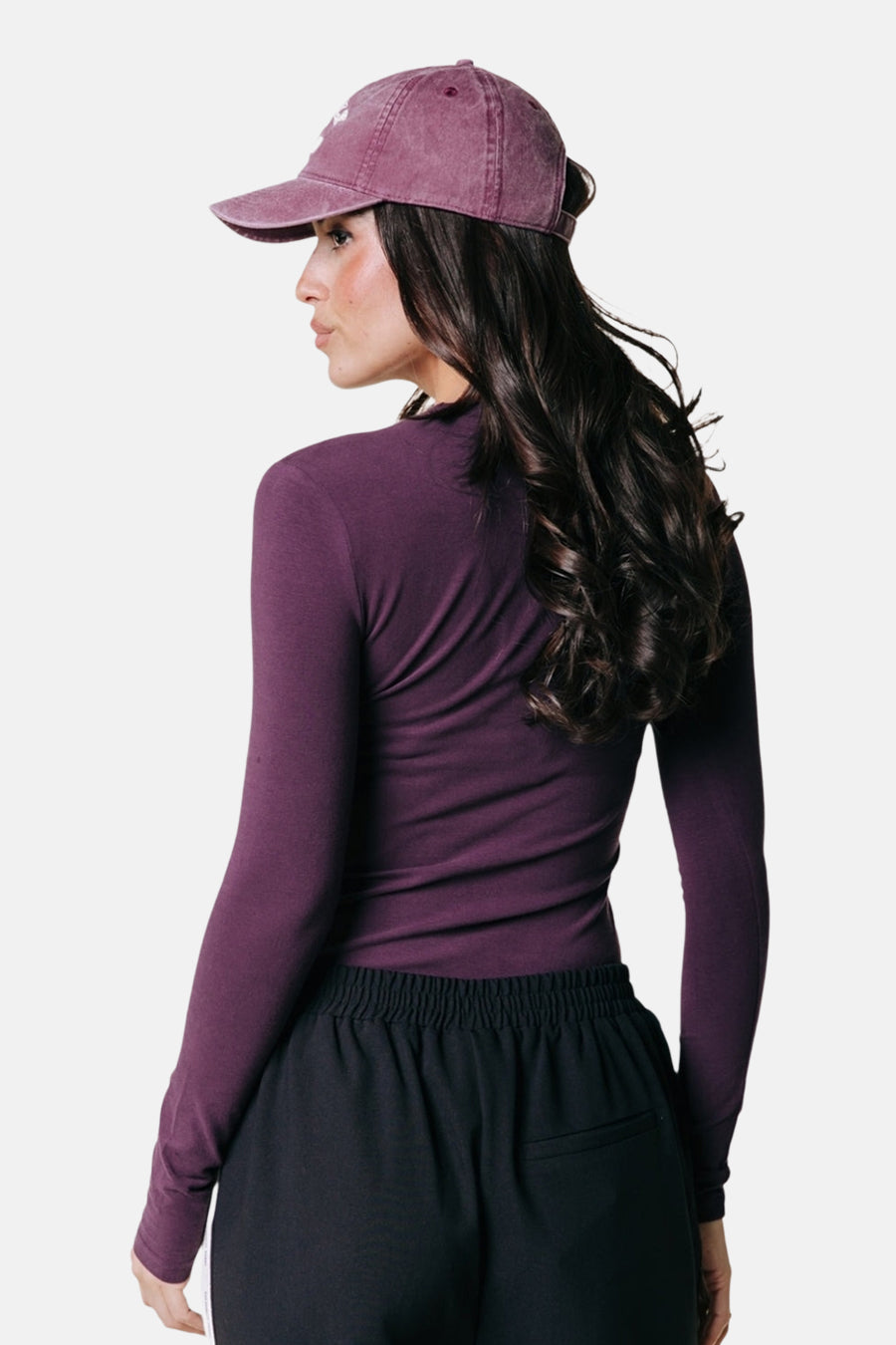 T-shirt à manches longues violet de COLOURFUL REBEL, avec pantalon foncé et casquette violette.