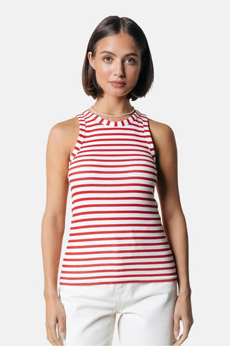 T-shirt sans manches rouge de COLOURFUL REBEL avec un motif à rayures, porté avec une chaîne de perles et un pantalon blanc.
