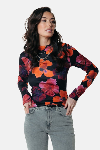 T-shirt multicolore à manches longues de COLOURFUL REBEL avec un motif floral, porté avec une chaîne argentée et des jeans gris.