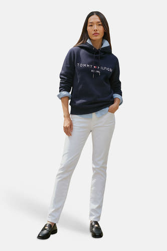 Sweat à capuche bleu de Tommy Hilfiger, porté avec une chemise bleu clair et un jean blanc.