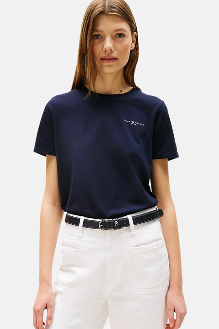 T-shirt bleu à manches courtes de TOMMY HILFIGER, porté avec un pantalon blanc et des chaussures loafers.