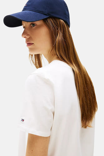 T-shirt blanc à manches courtes de TOMMY HILFIGER, avec un petit logo sur la manche, porté avec une casquette bleu marine.