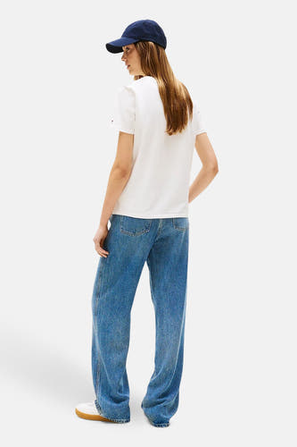 T-shirt blanc à manches courtes de TOMMY HILFIGER, vu de dos, associé à des jeans larges et une casquette bleu foncé.