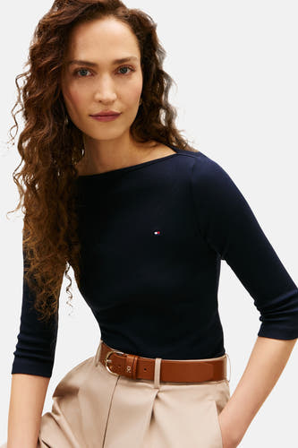 T-shirt bleu marine à manches courtes de Tommy Jeans, avec une ceinture marron sur un pantalon beige.