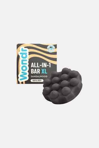 Bar tout-en-un XL santal foncé de WONDR CARE avec structure à picots, à côté de l'emballage.