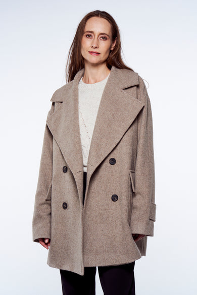 Veste grise YŪGEN, croisée avec de larges revers, portée par-dessus un pull en maille.