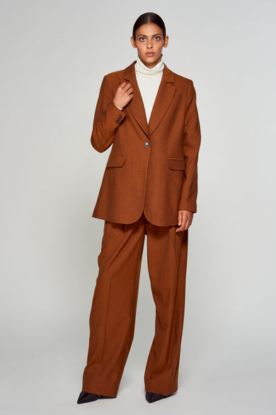 Blazer marron de YŪGEN porté sur une chemise blanche avec un pantalon large coordonné.