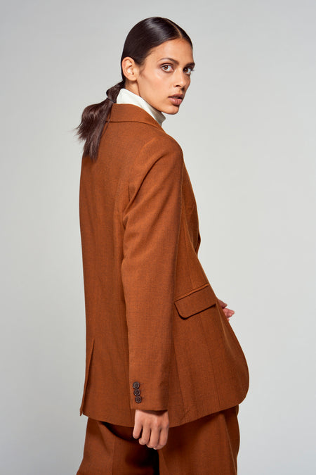 Blazer marron de YŪGEN, avec une coupe cintrée et des boutons visibles, associé à un gilet blanc.