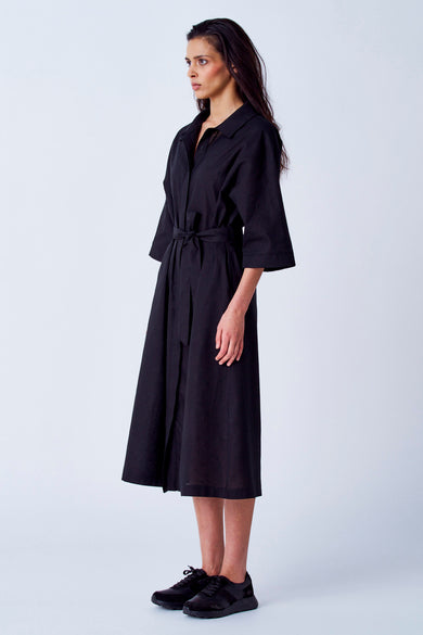 Robe noire à manches courtes de YŪGEN, avec ceinture et sneakers noires.