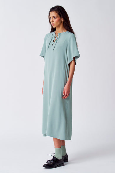 Robe verte avec manches courtes de YŪGEN, à encolure bénitier et portée avec des chaussettes vertes et des chaussures noires.