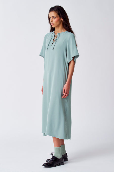 Robe verte avec manches courtes de YŪGEN, à encolure bénitier et portée avec des chaussettes vertes et des chaussures noires.