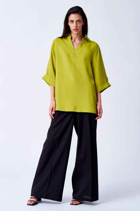 Blouse jaune à manches trois-quarts de YŪGEN, portée avec un pantalon noir large et des sandales.