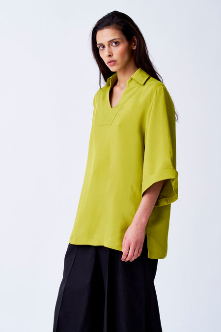 Blouse jaune à manches trois-quarts de YŪGEN, portée avec un pantalon noir, contre un fond blanc.