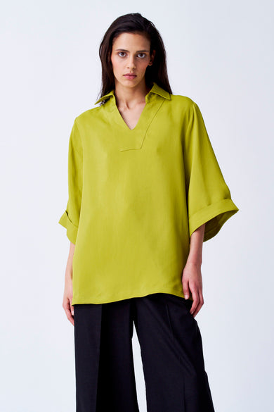 Blouse jaune à manches trois-quarts de YŪGEN, avec un col V et une jupe noire.