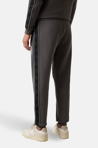 Grijze joggingbroek van Guess met logoprint op de zijkant en crèmekleurige schoenen.
