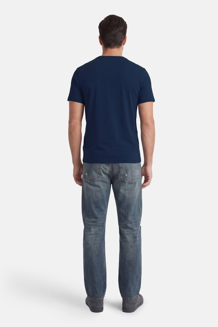 T-shirt bleu à manches courtes de Guess®, vu de dos, combiné avec un jean et des chaussures gris foncé.