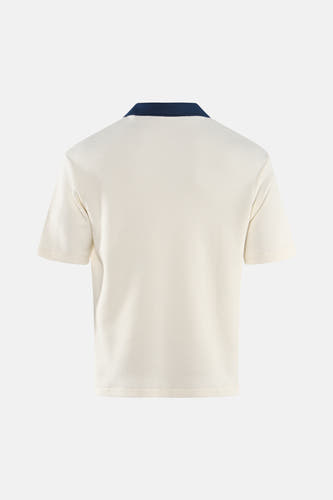 Polo écru à manches courtes de Guess, avec un col bleu foncé et une texture subtile.