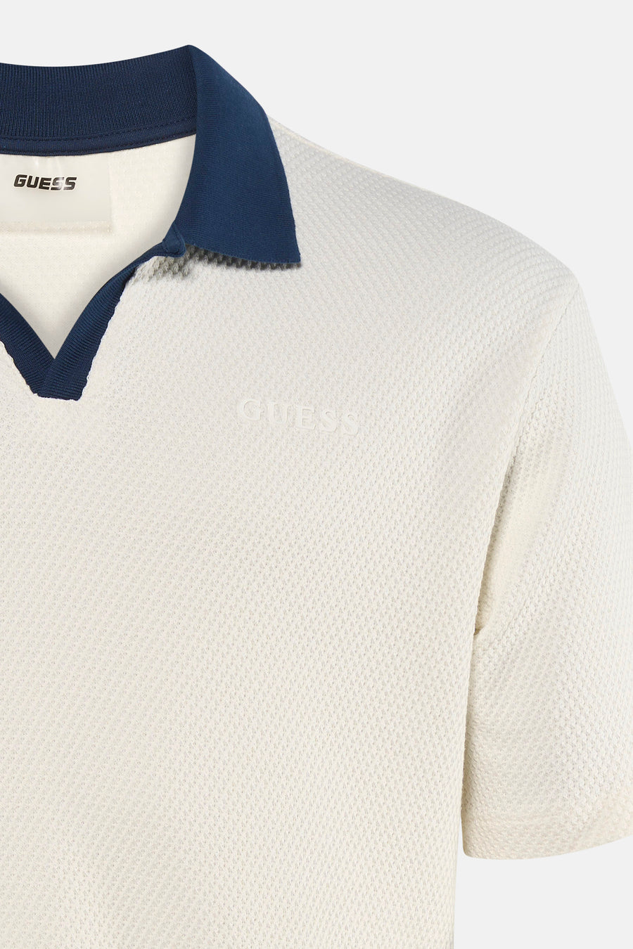 Polo écru à manches courtes de Guess, avec col bleu marine et texture subtile.
