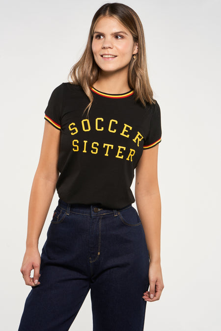 T-shirt noir de ZEB STYLE LAB à manches courtes et texte "Soccer Sister", combiné avec un jean bleu foncé.