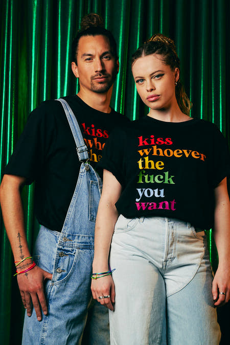 T-shirt noir de ZEB STYLE LAB, avec du texte arc-en-ciel et porté avec un short en denim.